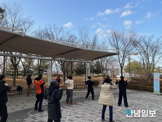 화성특례시 병점구보건소가 운영하는 비만 예방 프로그램 ‘온가족 공원체조’에 참여한 시민들이 공원에서 체조를 하고 있다